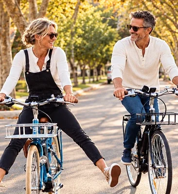 Couple riding bikes down a tree-lined street in autumn